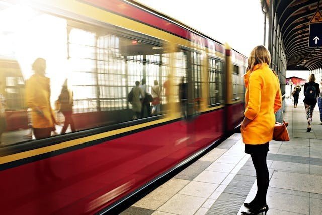 A woman in a yellow jacket standing near a train